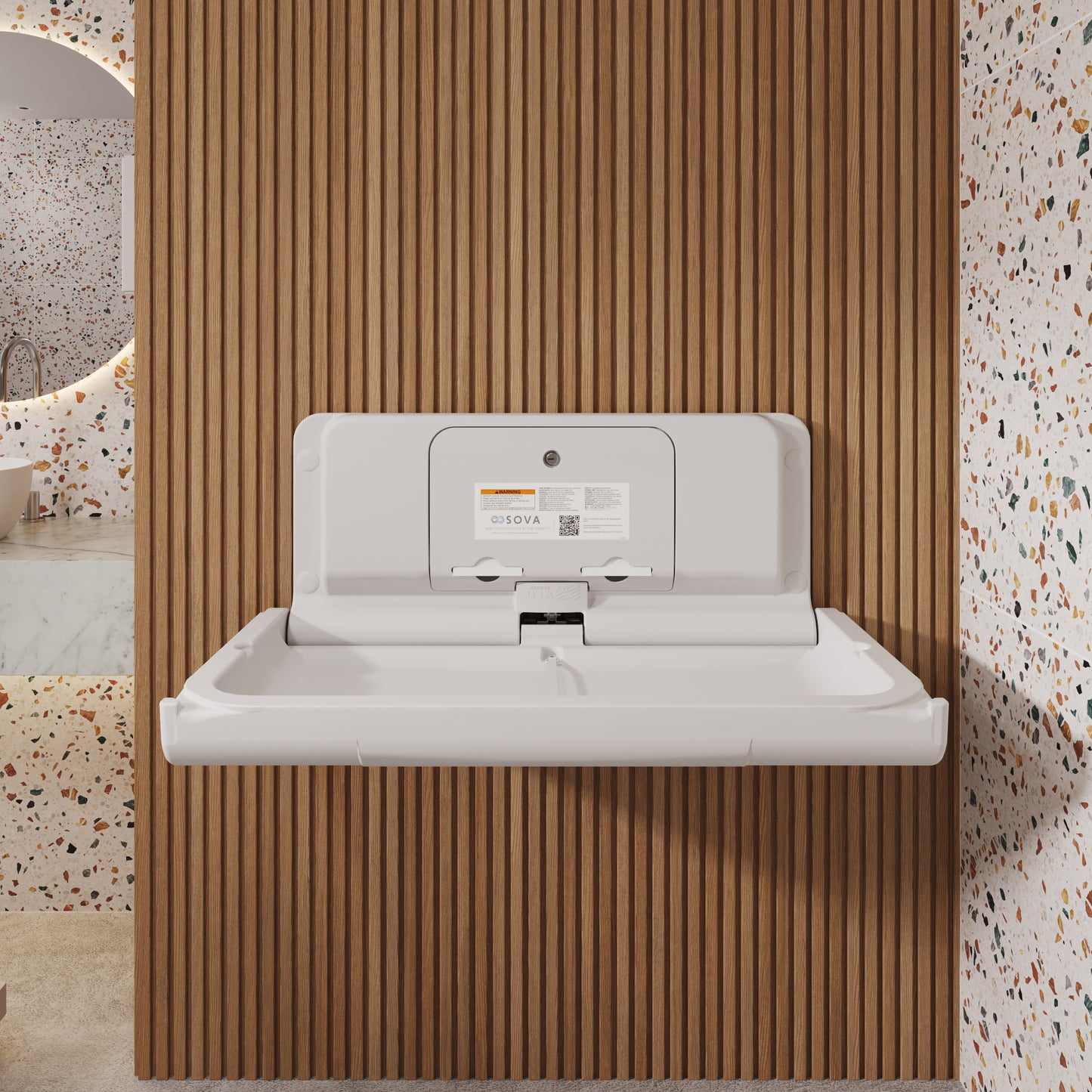 White Sova Span Horizontal Baby Changing Station front open mounted on a wooden panel with a terrazzo patterned floor and wall.