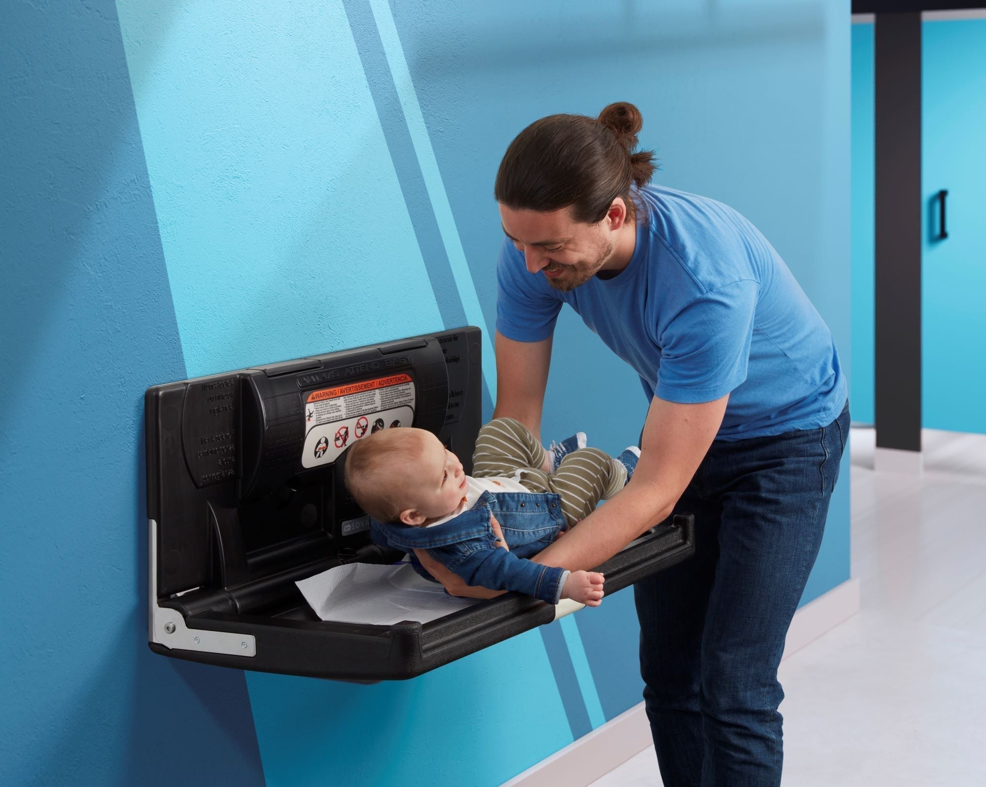Father changing baby on a baby changing table