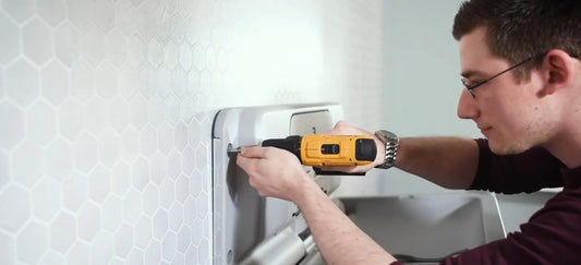 A man installing the 200-EH-01 Baby Changing Station into the wall.