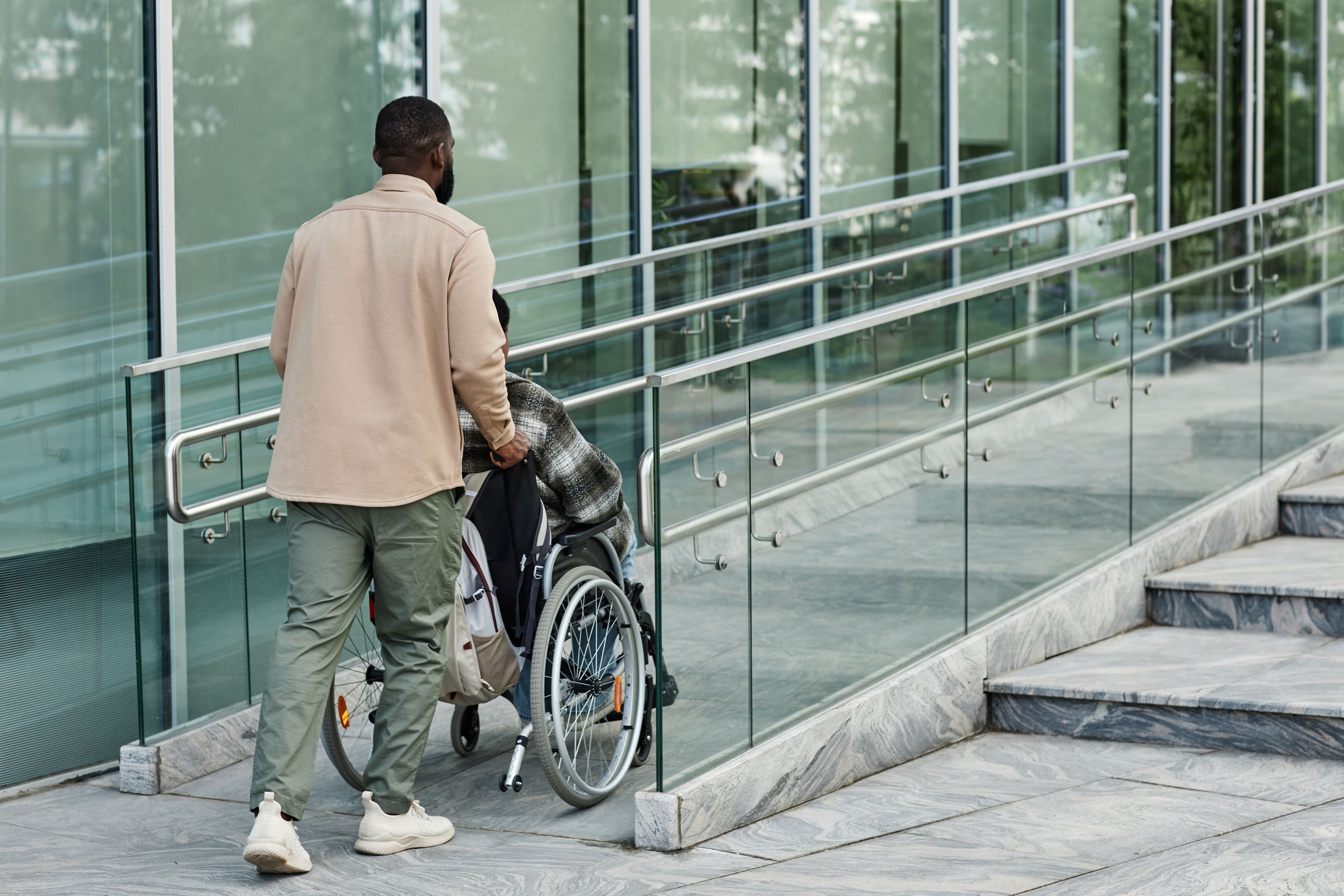 Man pushing a man in a wheelchair up a ramp