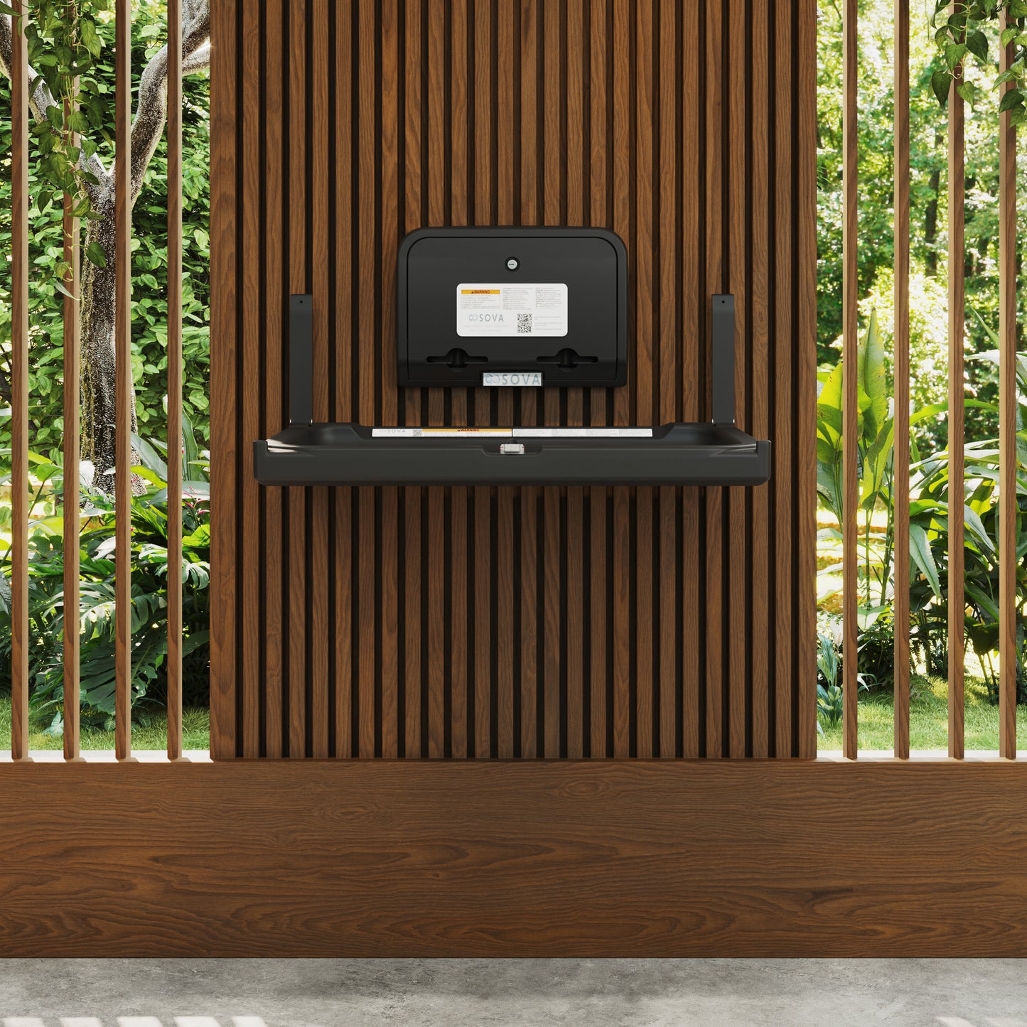 Black Element Baby Changing Station with Liner Dispenser on a wooden shelf against a wooden wall with greenery in the background