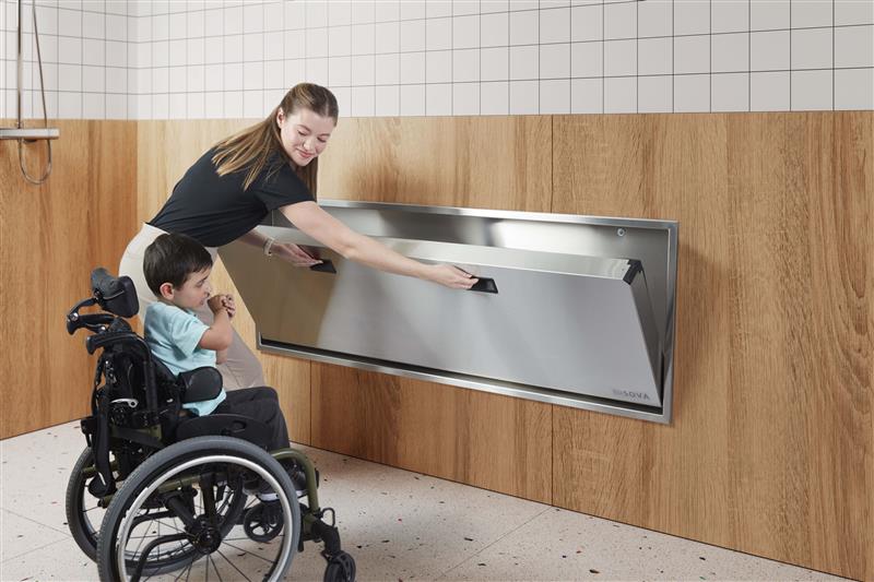 Person assisting a child in a wheelchair along Solace Extended Changing Station