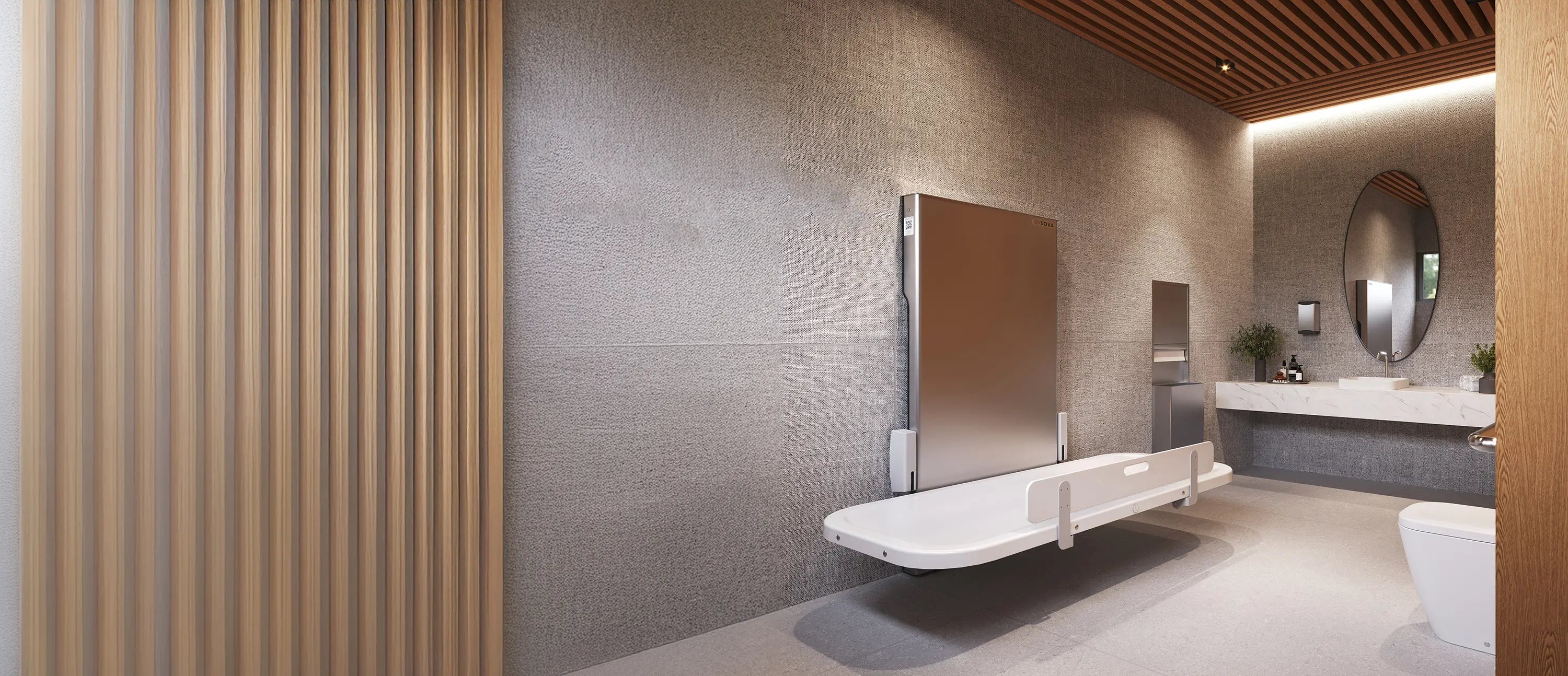 Sova Attend Adult Changing table in a modern bathroom interior with a sink, mirror, and decorative wall panels.