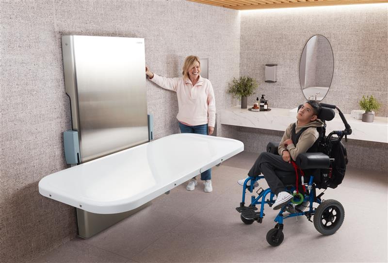 Person in a wheelchair sitting near an adult changing table