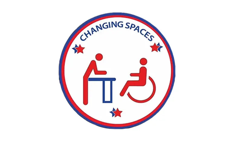 Logo of 'Changing Spaces' with icons of a person and a person in a wheelchair inside a red circle on a white background.